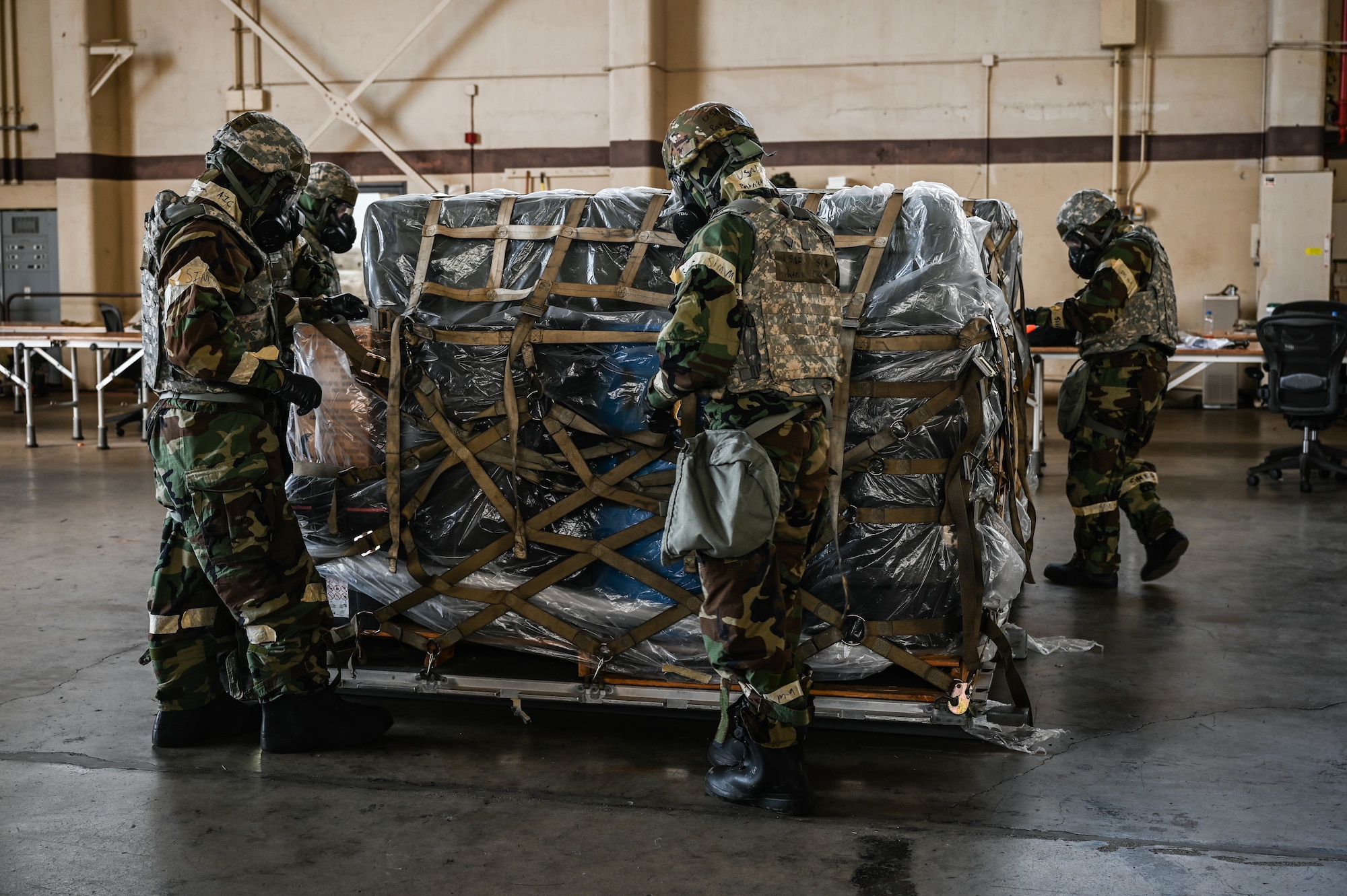 Airmen assigned to the 647th Logistics Readiness Squadron combat mobility flight palletize cargo while in Mission-Oriented Protective Posture gear during Exercise TROPIC FURY at Joint Base Pearl Harbor-Hickam, Hawaii, March 8, 2022. MOPP gear is utilized during chemical, biological, radiological, nuclear and high yield explosives scenarios, protecting Airmen from contamination and allowing them to continue to support mission-critical tasks. (U.S. Air Force photo by Staff Sgt. Alan Ricker)