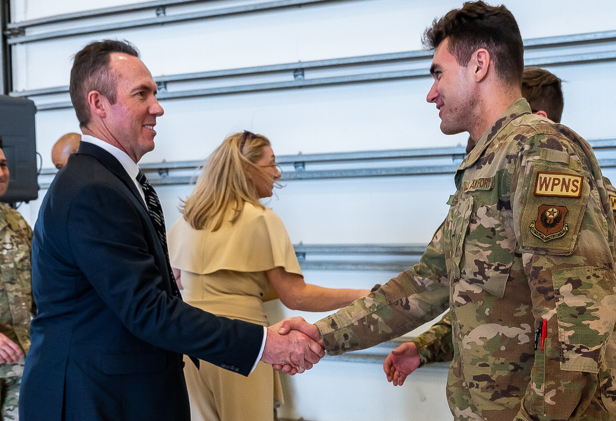 An Airman shakes hands with a man in a business suit.