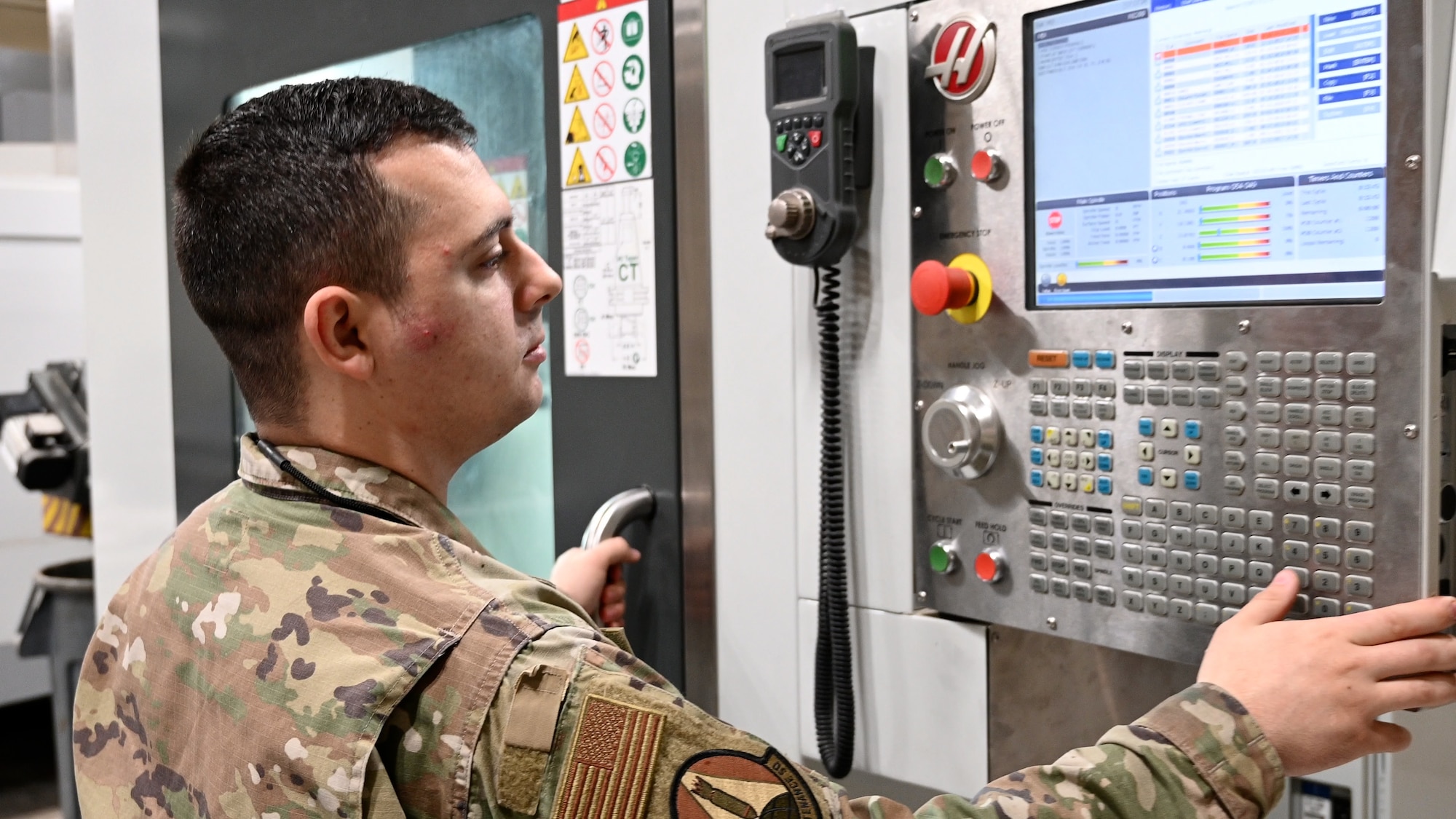 A man in uniform pushes a button on a machine.