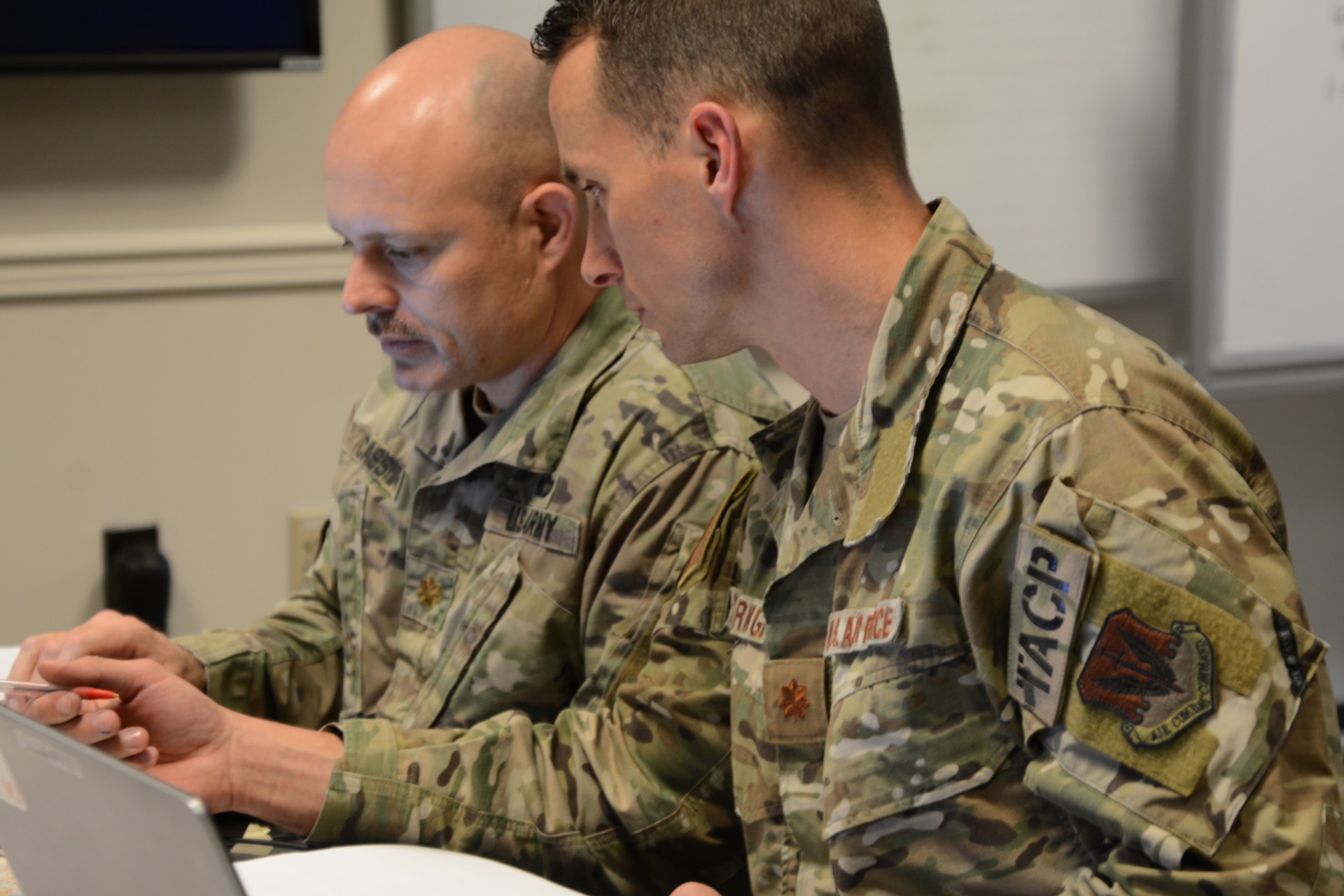 Army Maj. Justin Cassidy, future operations officer, and Air Force Maj. Shawn Bearinger, Air future operations officer, discuss plan options during a staff training course March 8 at Fort Indiantown Gap, Pennsylvania. The trial course, hosted by U.S. Northern Command, will be the Phase II of the Joint Staff Training Course.  The course trained staff on emergency preparedness using a notional Category 2 Hurricane scenario.