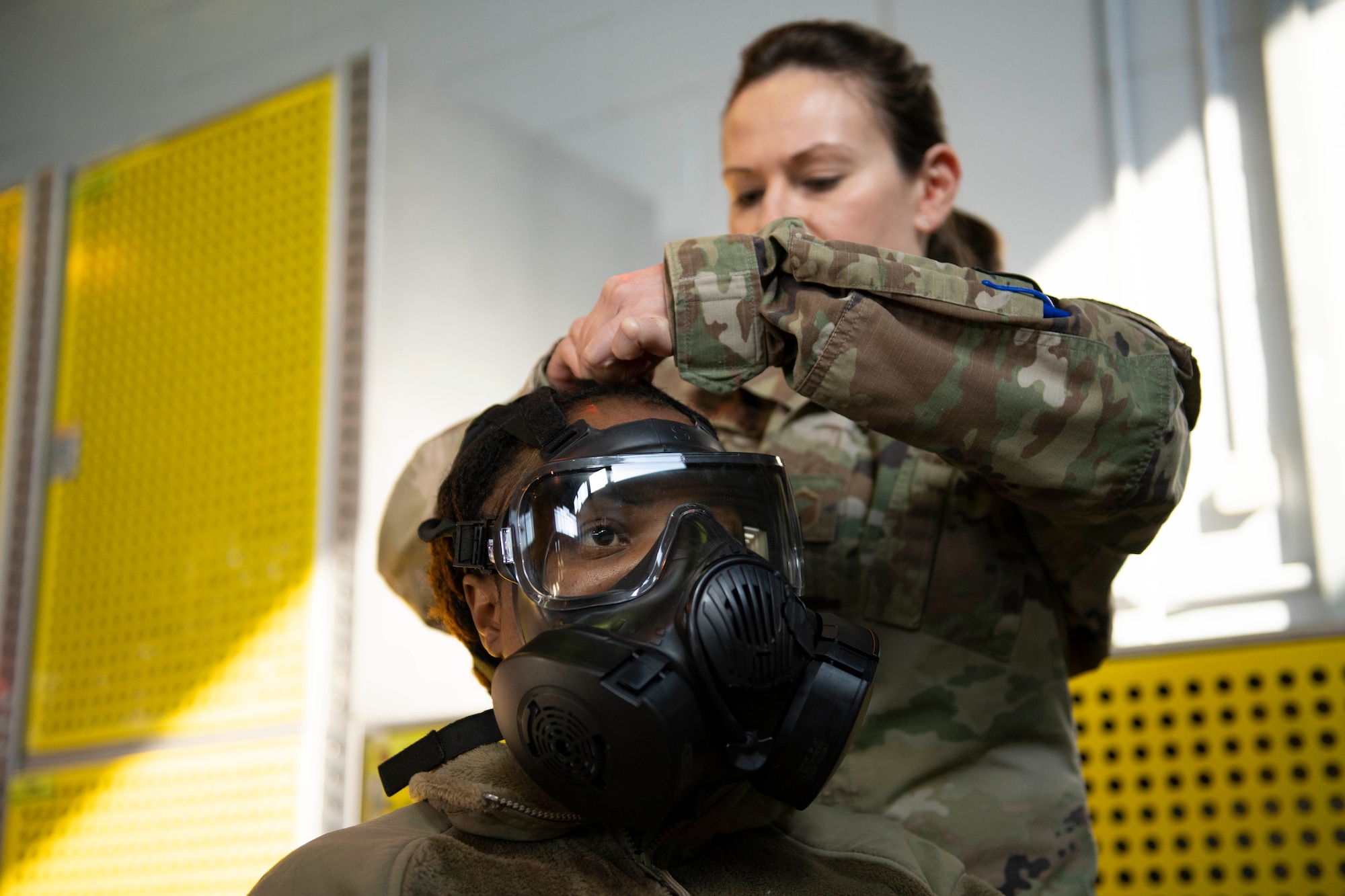 U.S. Air Force Master Sgt. Terri Adams, 423rd Civil Engineer Squadron NCO in charge of emergency management, inspects Tech. Sgt. Princess Okai, 501st Combat Support Wing Equal Opportunity director, Mission Oriented Protective Posture (MOPP) gear for proper wear during chemical, biological, radiological and nuclear (CBRN) training at RAF Alconbury, England, March 8, 2022. Airmen conduct buddy checks when MOPP gear is put on, to look for holes or areas where CBRN agents could reach the skin or airway. (U.S. Air Force photo by Senior Airman Jennifer Zima)