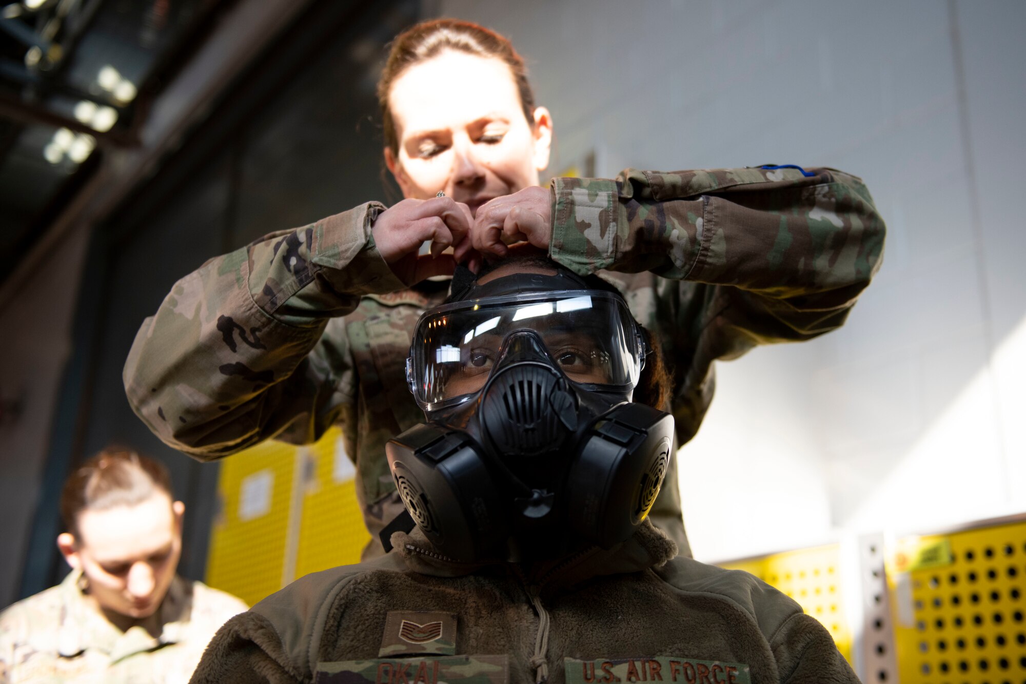U.S. Air Force Master Sgt. Terri Adams, 423rd Civil Engineer Squadron NCO in charge of emergency management, inspects Tech. Sgt. Princess Okai, 501st Combat Support Wing Equal Opportunity director, Mission Oriented Protective Posture (MOPP) gear for proper wear during chemical, biological, radiological and nuclear (CBRN) training at RAF Alconbury, England, March 8, 2022. Airmen conduct buddy checks when MOPP gear is put on, to look for holes or areas where CBRN agents could reach the skin or airway. (U.S. Air Force photo by Senior Airman Jennifer Zima)