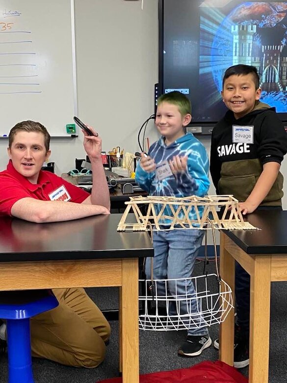 Middle East District civil engineer Garrison Myers, P.E., assists students with weight testing their bridge, following a presentation he gave on general engineering principles and his own personal experiences with engineering, at the DoD-sponsored STARBASE Academy Winchester, Va.