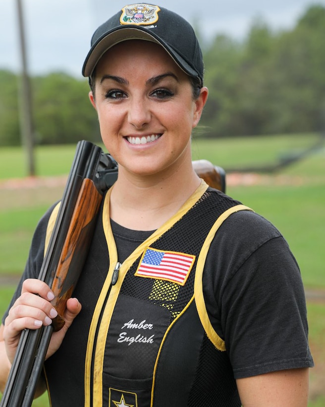 A woman poses for a photo holding a shotgun over her shoulder.