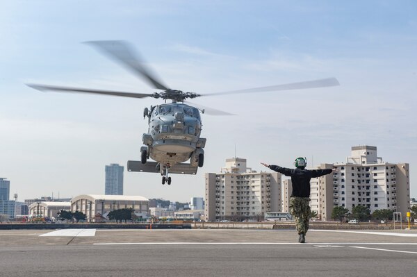 YOKOSUKA, Japan (March 10, 2022) Aviation Electronics Technician 3rd Class Bradley Douglas, from Latrobe, Pennsylvania, signals an MH-60R Seahawk, attached to the “Saberhawks” of Helicopter Maritime Strike Squadron (HSM) 77, to land at Commander, Fleet Activities Yokosuka. HSM-77 is attached to Commander, Task Force 70 and forward-deployed to the U.S. 7th Fleet area of operations in support of a free and open Indo-Pacific. (U.S. Navy photo by Mass Communication Specialist 2nd Class Erica Bechard)