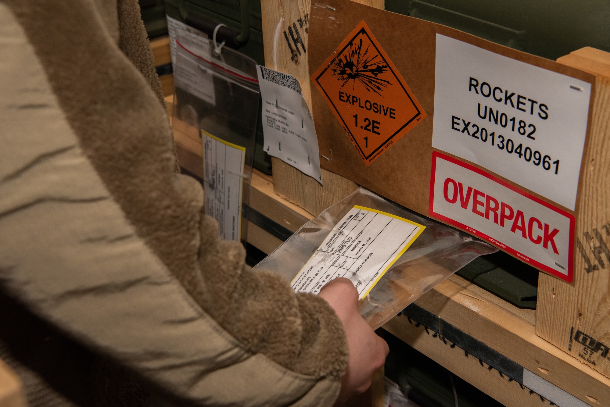 An Air Force Airman is looking at a tag attached to a container containing rockets.