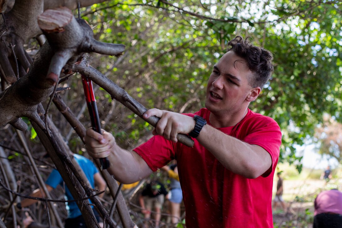 A volunteer cuts a tree during a cleanup at Kapapuhi point park, Oahu, HI, Feb. 26, 2022. Groups from around Oahu got together with Malama Puuloa to restore the area near Pearl Harbor. (U.S. Marine Corps photo by Cpl. Jose Angeles)