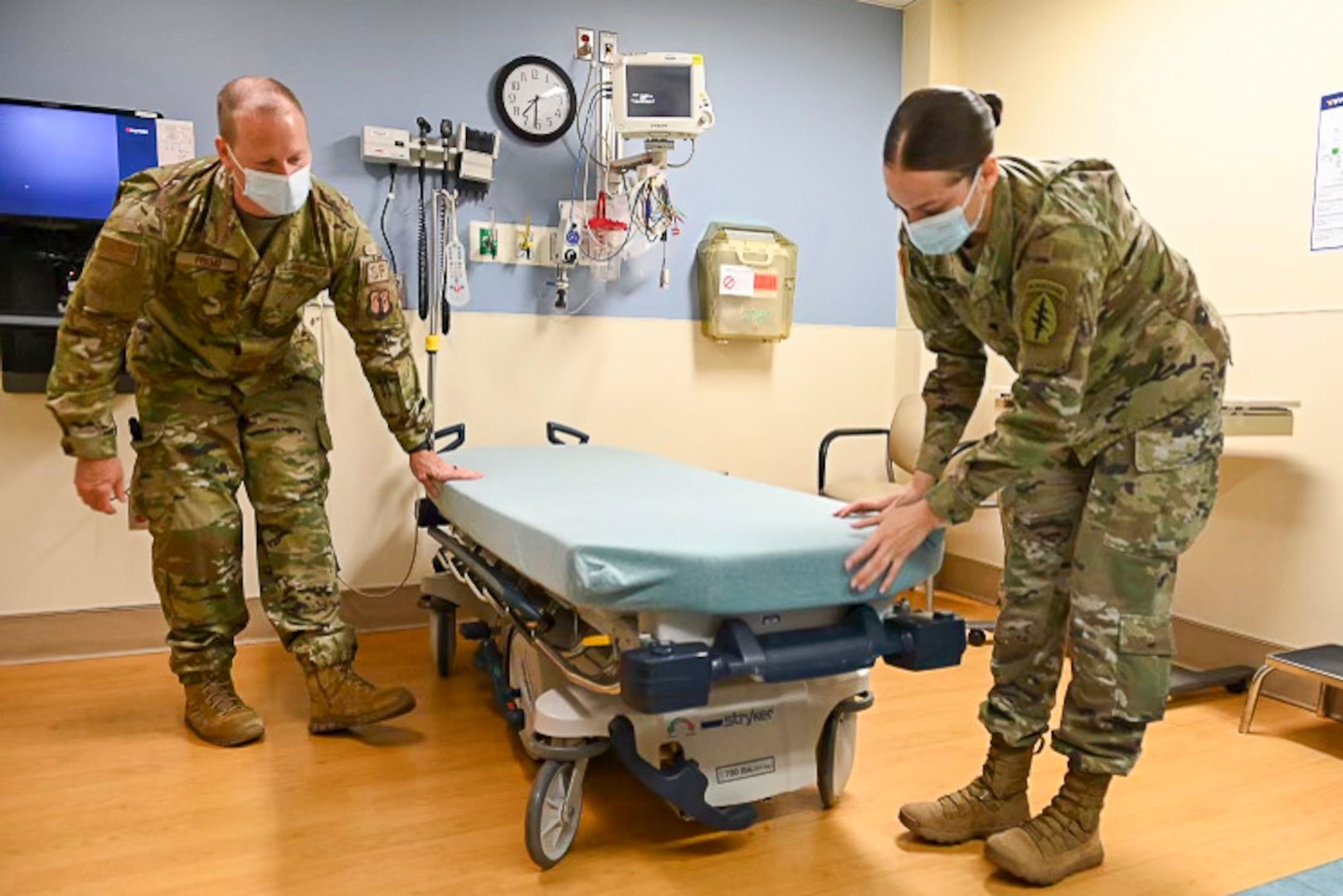 U.S. Air Force Master Sgt. Derek Premo, a flight chief for the 167th Security Forces Squadron, and U.S. Army Spc. Tamara Bumgardner, a motor vehicle operator for the 1528th Forward Support Company, Special Operations (Airborne), prepare a patient examination bed in a room at Jefferson Medical Center in Ranson, West Virginia. West Virginia Guardsmen have been assisting in hospitals throughout the state since January.