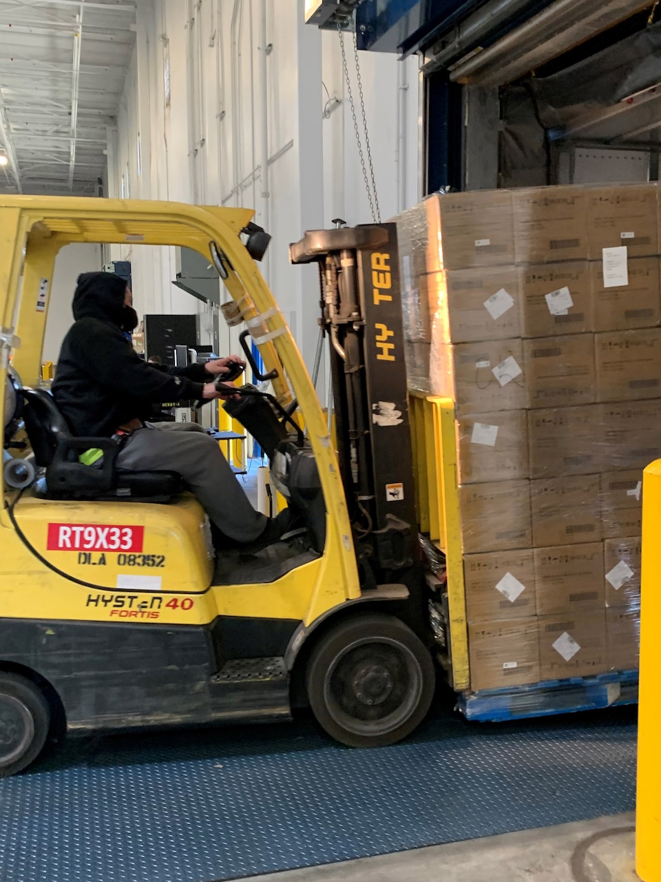 A man drives a forklift carrying COVID-19 test kits.