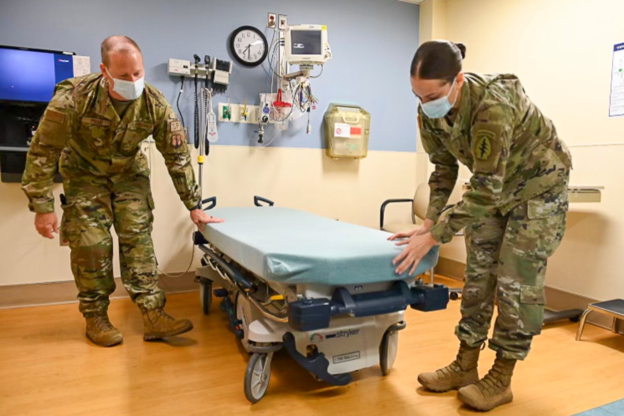 U.S. Air Force Master Sgt. Derek Premo, a flight chief for the 167th Security Forces Squadron, and U.S. Army Spc. Tamara Bumgardener, a motor vehicle operator for the 1528th Forward Support Company, Special Operations (Airborne), prepare a patient examination bed in a room at Jefferson Medical Center in Ranson, West Virginia. West Virginia Guardsmen have been assisting in hospitals throughout the state since January as requested by West Virginia Governor Jim Justice.