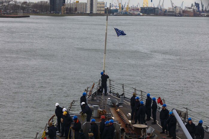 220312-N-EM691-1004 ROTTERDAM, Netherlands (March 12, 2022) ¬– Sailors, assigned to the Arleigh Burke-class guided-missile destroyer USS The Sullivans (DDG 68) hoist the flag during sea and anchor upon arrival to Rotterdam, Netherlands for a scheduled port visit, Mar. 12. The Sullivans is operating in the European theater of operations and participating in a range of maritime activities in support of U.S. Sixth Fleet and NATO Allies.