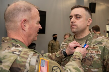 Maj. Gen. Timothy P. Williams, the Adjutant General of Virginia, pins the Air Force Commendation medal on an Airman from the 185th Cyberspace Operations Squadron at an end of mobilization ceremony for recently mobilized Airmen Feb. 25, 2022, in Hampton, Virginia.