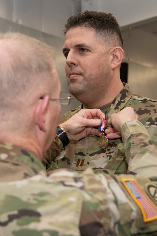 Maj. Gen. Timothy P. Williams, the Adjutant General of Virginia, pins the Meritorious Service Medal on an Airman from the 185th Cyberspace Operations Squadron at an end of mobilization ceremony for recently mobilized Airmen Feb. 25, 2022, in Hampton, Virginia.