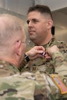 Maj. Gen. Timothy P. Williams, the Adjutant General of Virginia, pins the Meritorious Service Medal on an Airman from the 185th Cyberspace Operations Squadron at an end of mobilization ceremony for recently mobilized Airmen Feb. 25, 2022, in Hampton, Virginia.