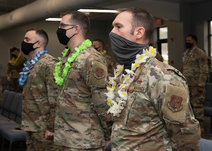 Three members of the 856th Cyber Protection Team stand with leis around their necks at an end of mobilization ceremony Feb. 25, 2022, in Hampton, Virginia.