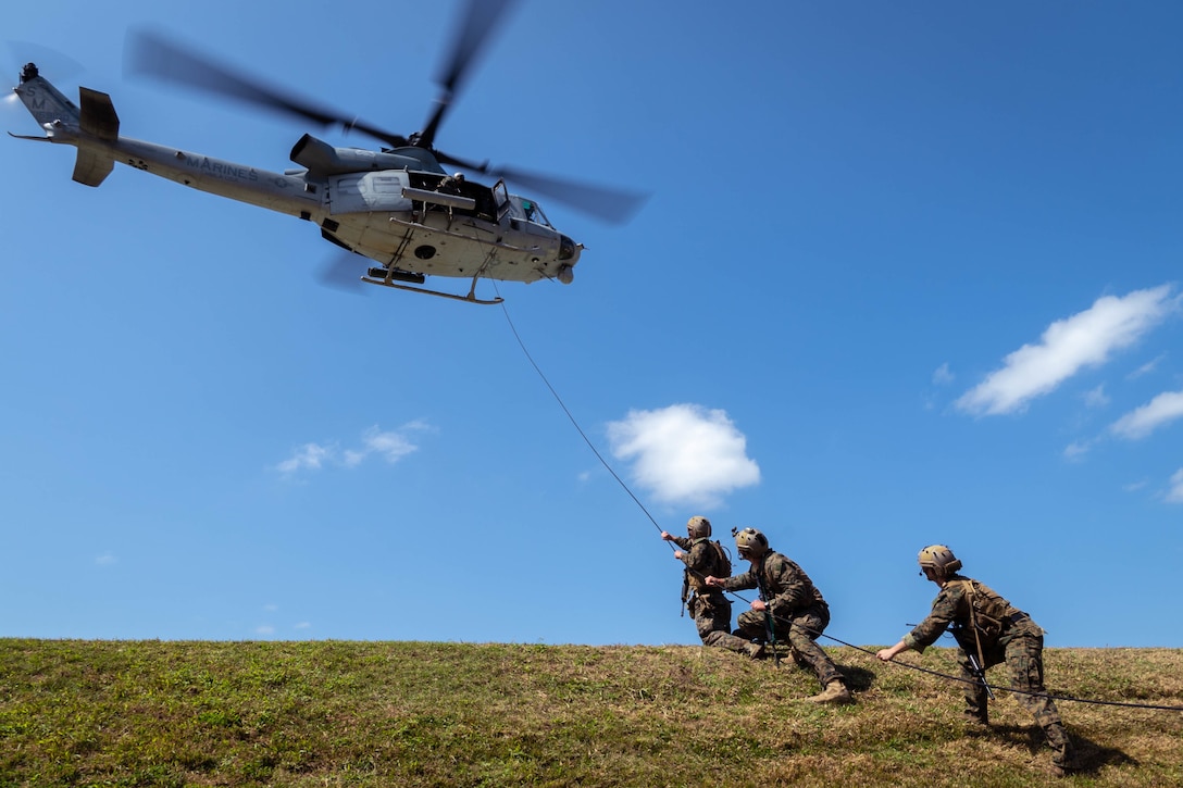 A helicopter hovers above a group of Marines.