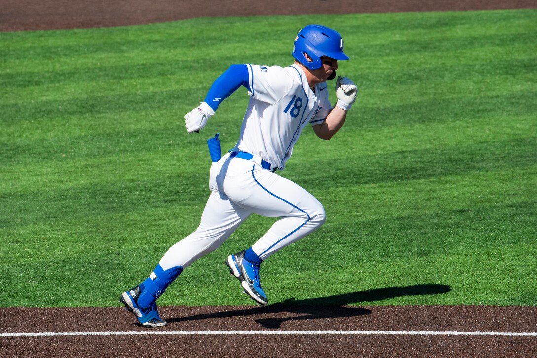 A baseball player runs along the baseline.