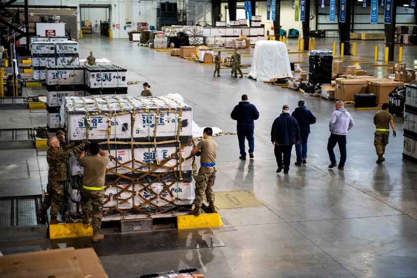 Three airmen secure equipment on a pallet bound for Ukraine.