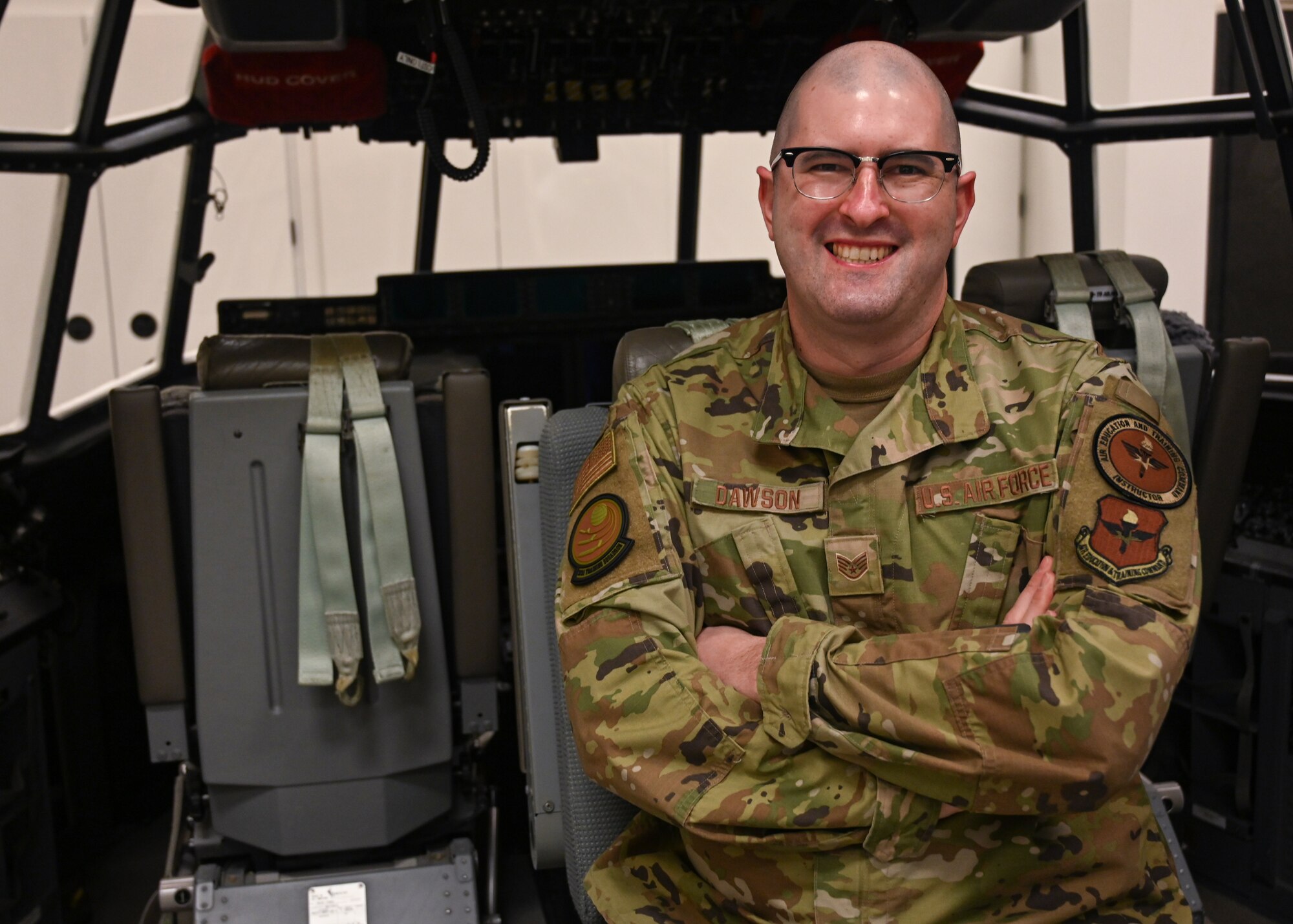 An Airman poses for a photo inside a C-130J Super Hercules flight deck trainer.