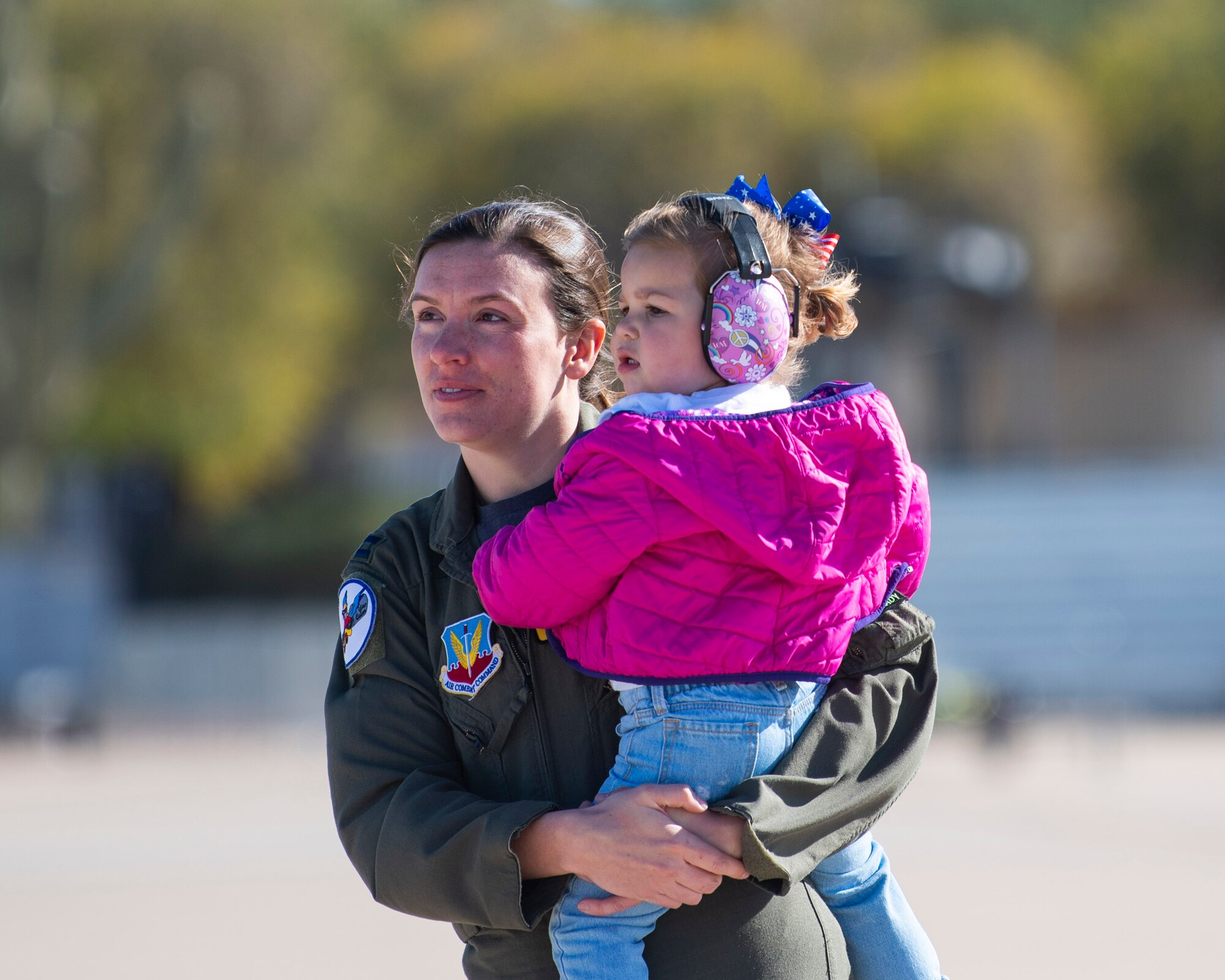 Mother and daughter wearing ear protection stand on the flightline.