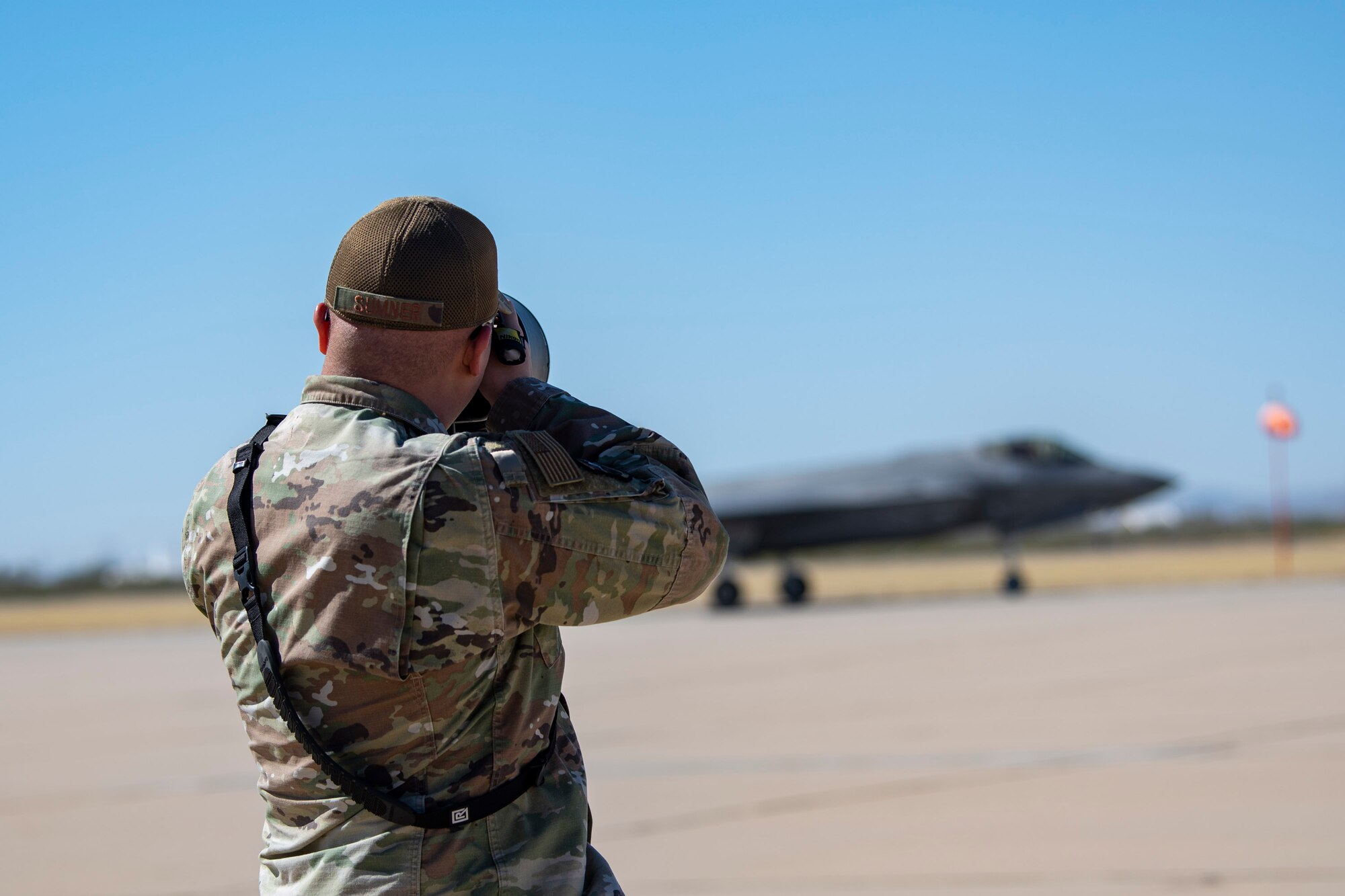 Man takes a photo of a plane taxiing on the flightline.