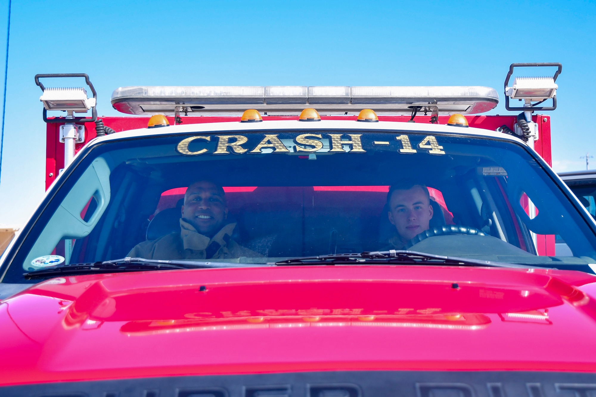 Two guys sit inside an emergency response vehicle.