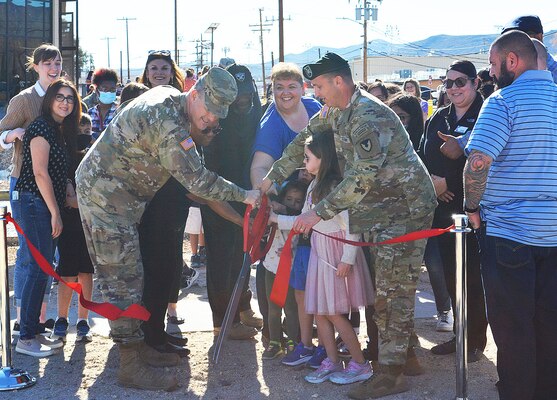 Brig. Gen. Curt Taylor, commanding general of the National Training Center at Fort Irwin, left, and Col. Jason Clarke, Fort Irwin garrison commander, right, get some assistance cutting the ribbon signifying the grand opening of the Fort Irwin Library during a ceremony March 9 at Fort Irwin, California. The U.S. Army Corps of Engineers Los Angeles District’s Fort Irwin Resident Office managed the construction of the facility.