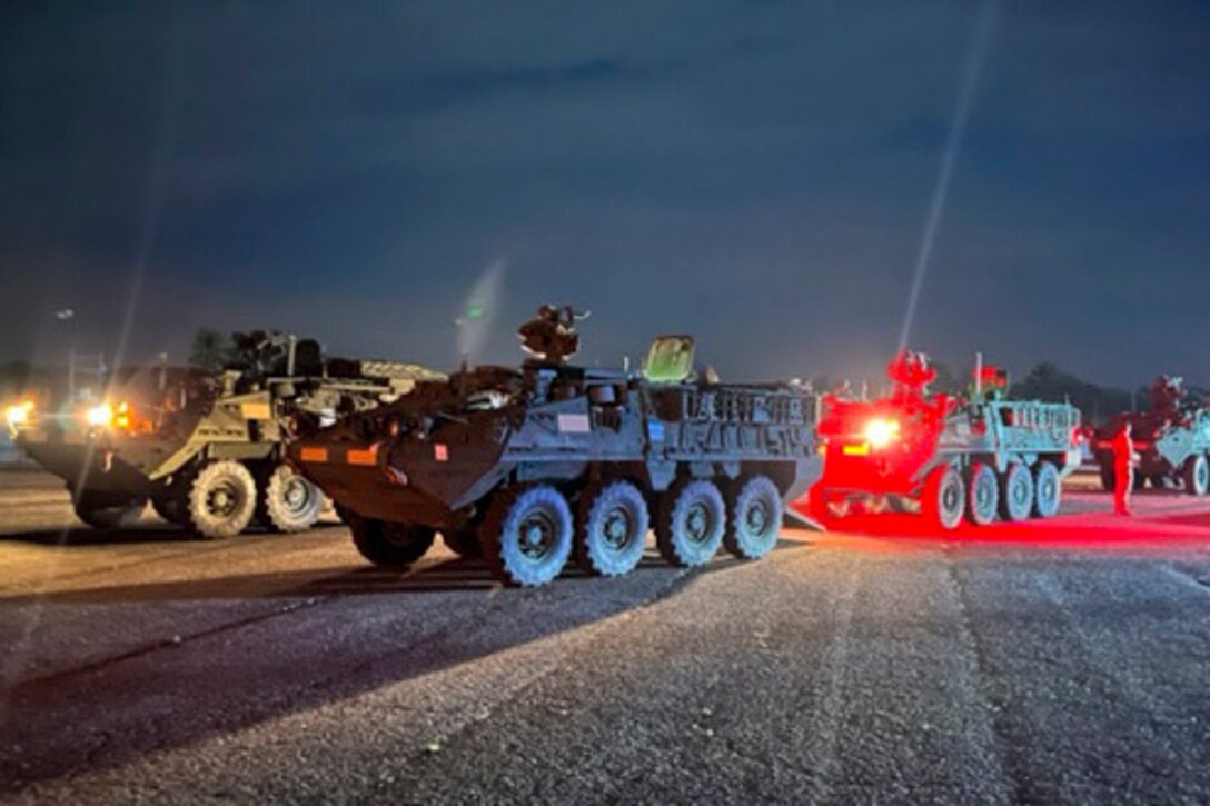 Military vehicles traveling at night.