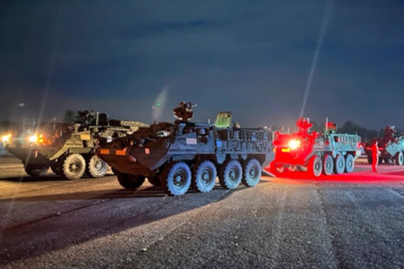 Military vehicles traveling at night.