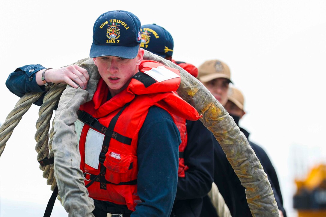 Sailors carry a large rope.