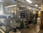 A man stands at a large printing machine.