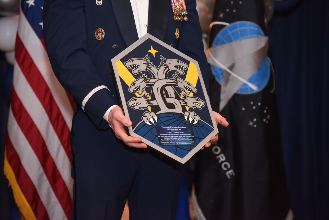 U.S. Air Force Col. Shay Warakomski, Peterson-Schriever Garrison commander, holds the Small Team of the Year plaque as he announces the 21st Operational Medical Readiness Squadron/ Pandemic team for the Small Team award winners at Peterson Space Force Base, Colorado, Mar. 11, 2022.