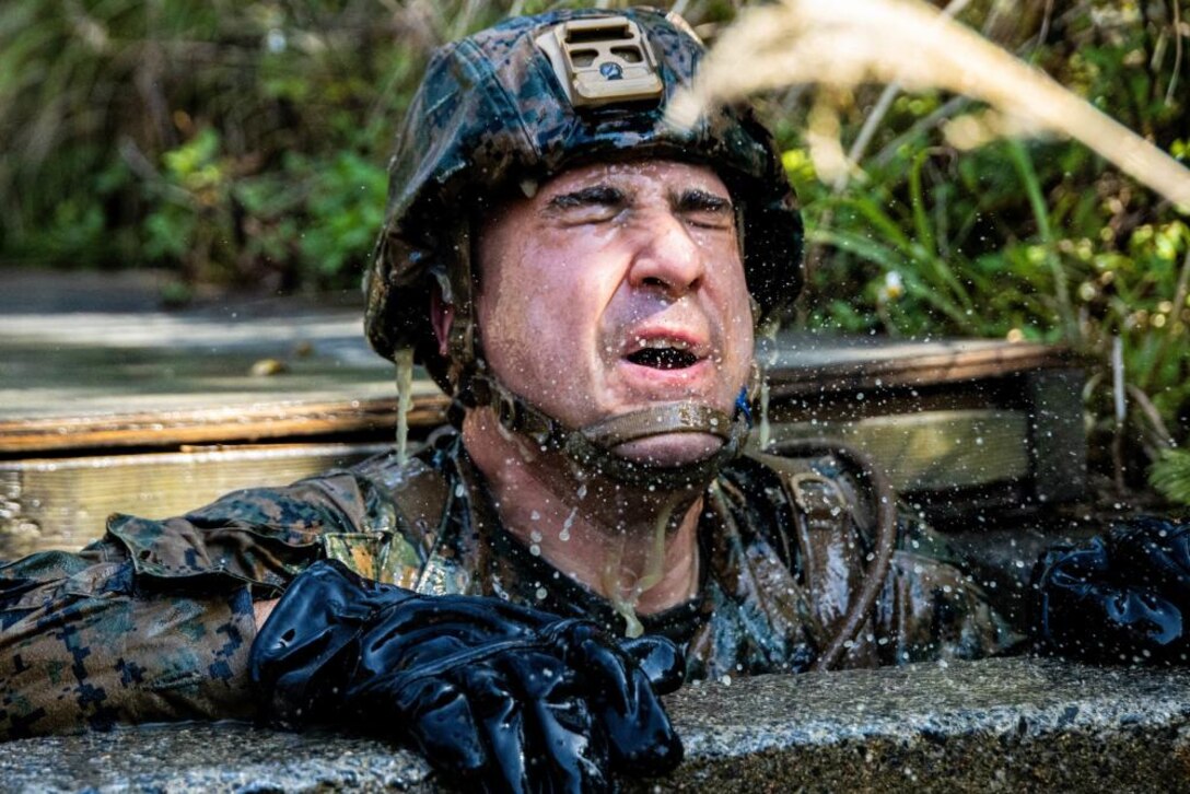 A U.S. Marine with 3rd Marine Expeditionary Brigade, moves through an underwater obstacle during a Jungle Warfare Training Center endurance course, March 3, 2022, at Camp Gonsalves, Okinawa, Japan. Throughout the course, Marines learned how to traverse, survive, and thrive in the jungle. (Marine Corps photo by Cpl. Zachary Sarvey)