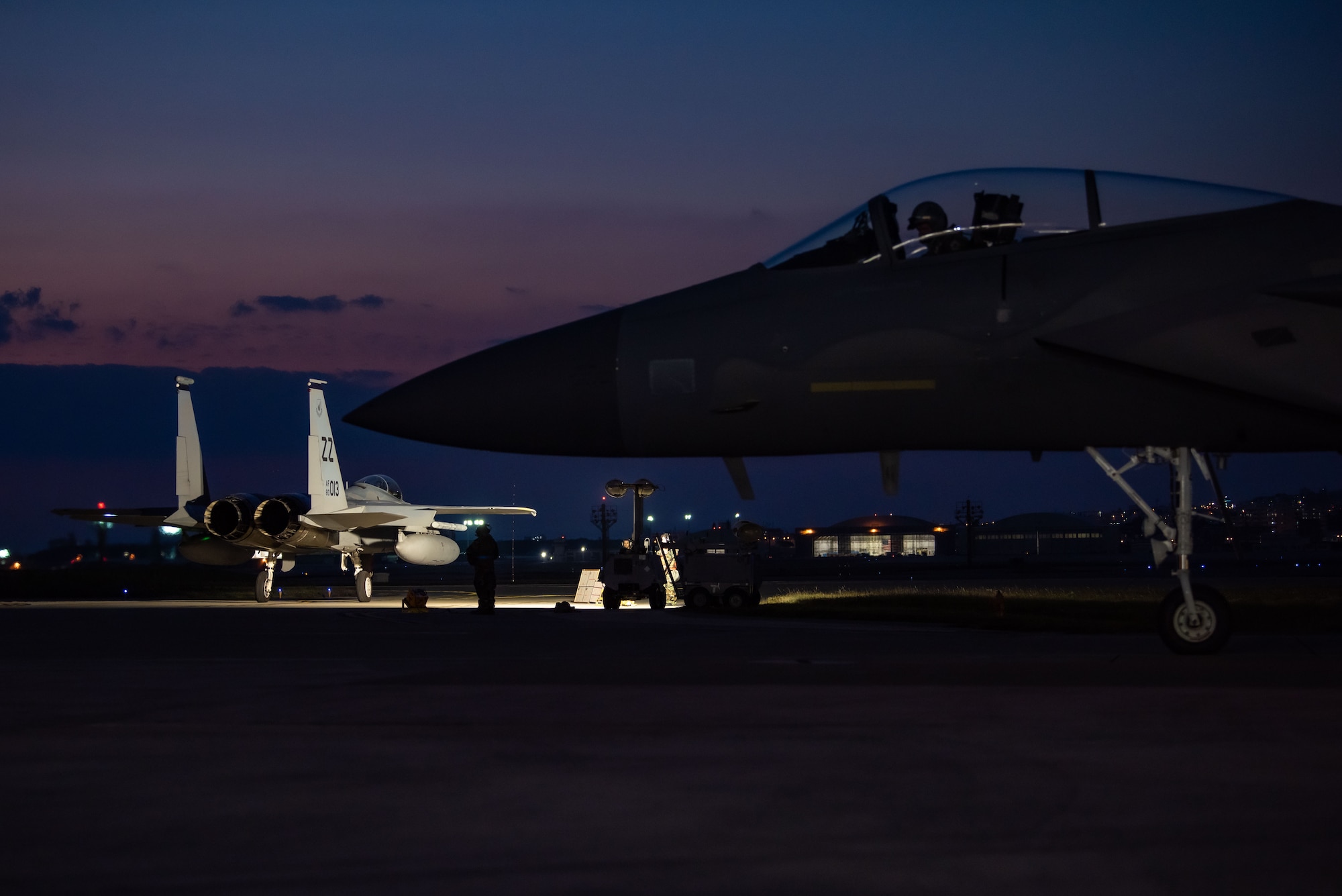 F-15C Eagles taxi on a flightline before takeoff at sunset.