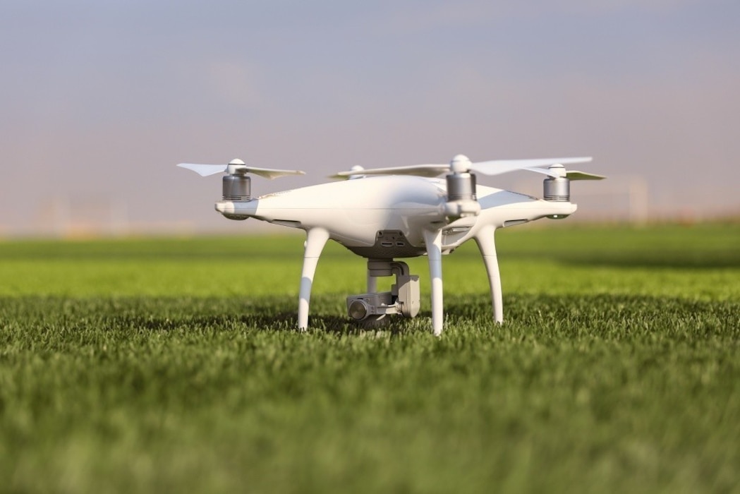 White drone sitting in grass field.