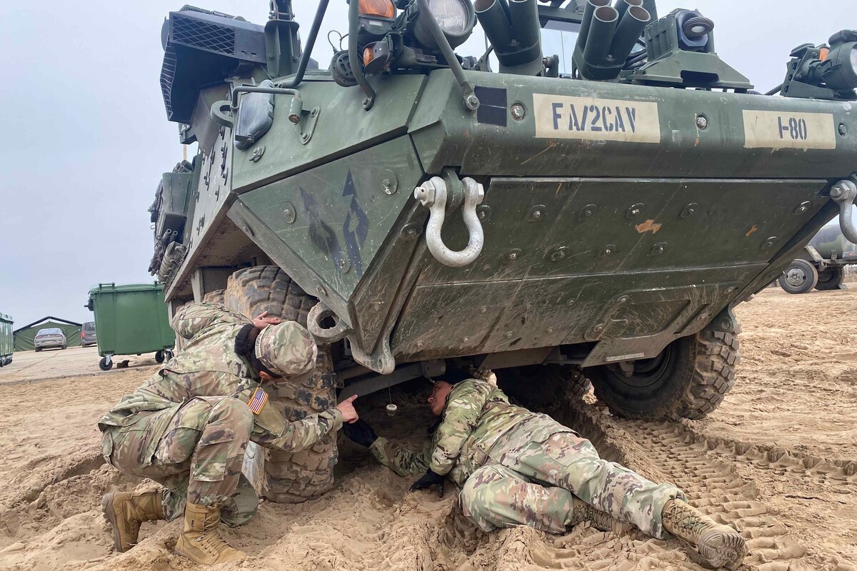 Soldiers inspect a tactical vehicle.