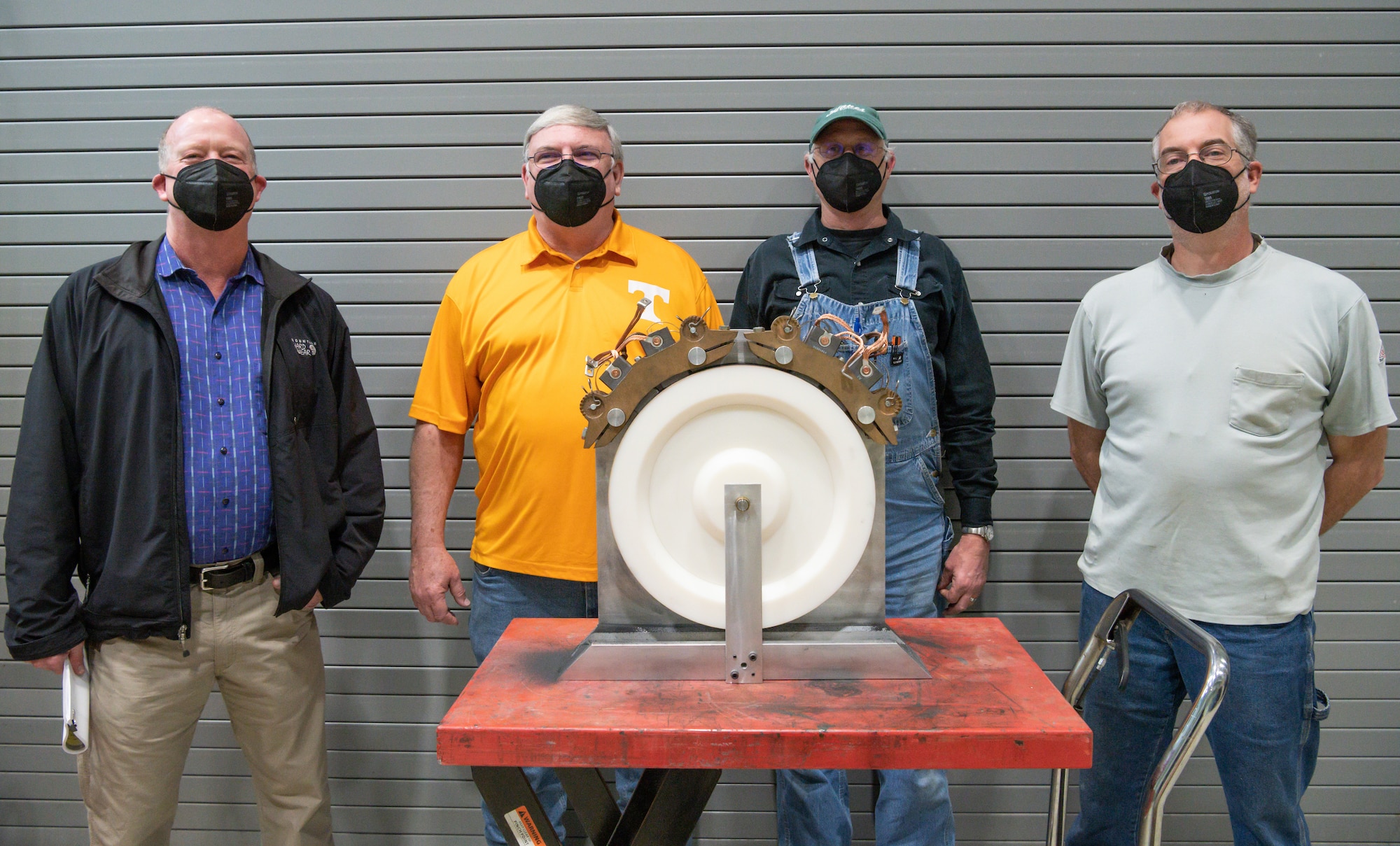 AEDC team members stand behind the device they designed and built to surface motor brushes.