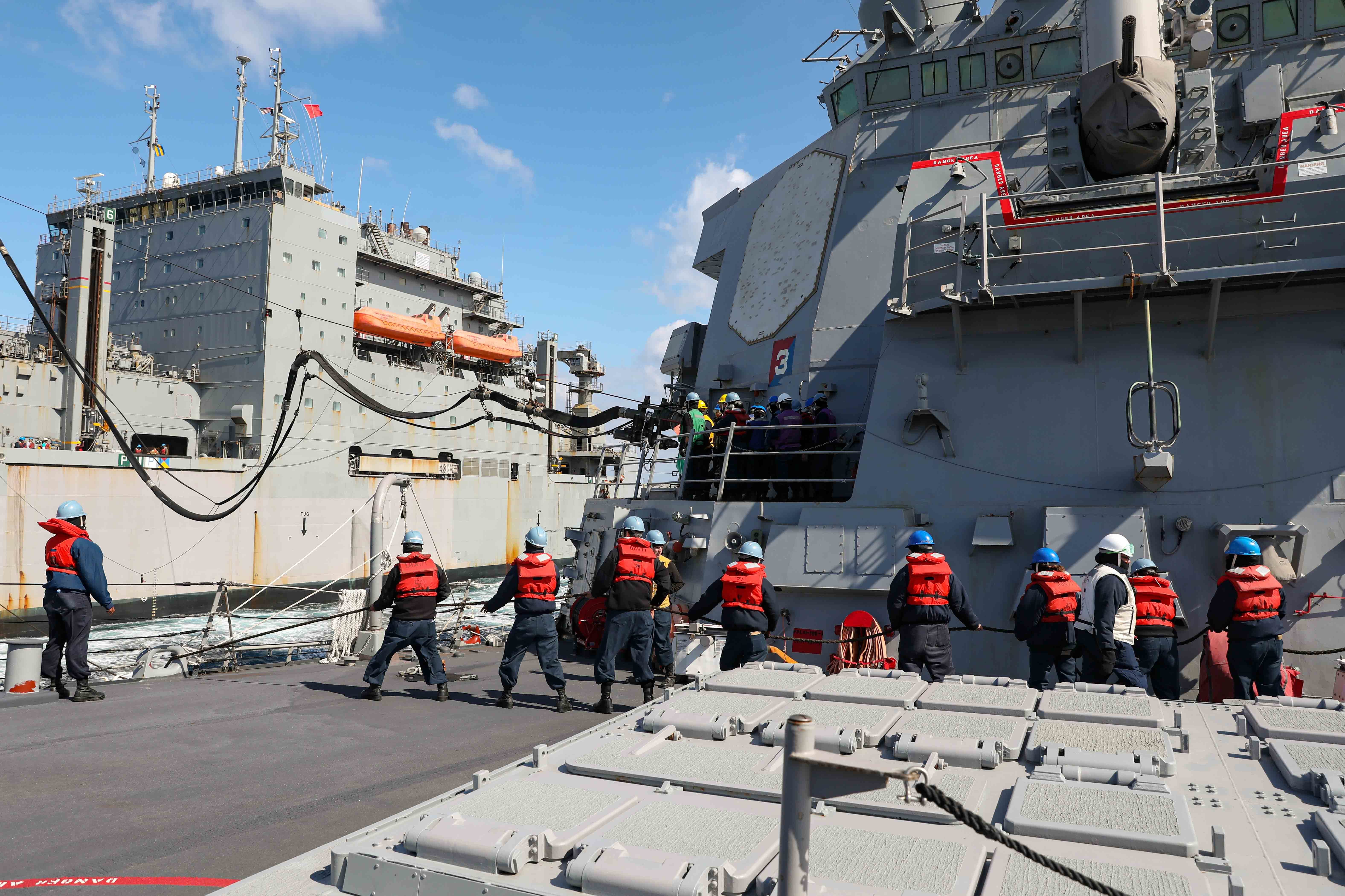 Sailors assigned to the Arleigh Burke-class guided-missile destroyer USS Ross (DDG 71) heave in a line during a replenishment-at-sea with the Lewis and Clarke-class dry cargo ship USNS Robert E. Peary (T-AKE 5), March 11.