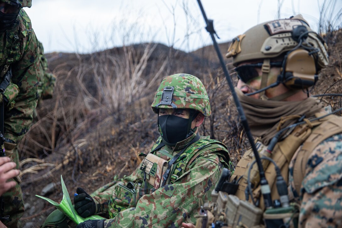 A company commander with the Amphibious Rapid Deployment Brigade (ARDB), communicates through a translator during an air assault training exercise, on Combined Arms Training Center (CATC) Camp Fuji, Japan, March 9, 2022. The training exercise was conducted to build proficiency in rapidly seizing and defending key terrain. Maritime Defense Exercise Amphibious Rapid Deployment Brigade (MDX-ARDB) is a bilateral exercise meant to increase interoperability and strengthen ties between U.S. and Japanese forces for the defense of Japan. (U.S. Marine Corps photo by Cpl. Malik Lewis)