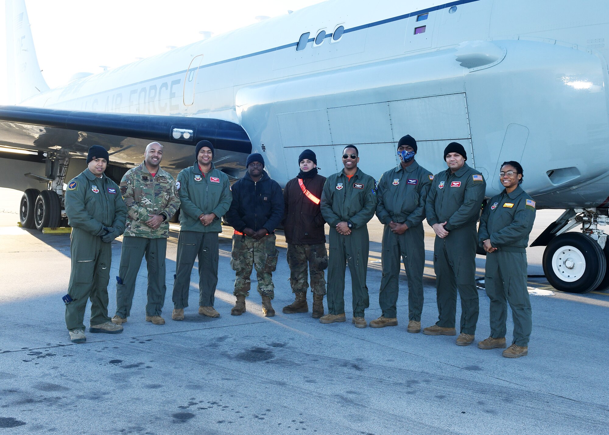 Airmen pose for a photo on the side of an aircraft.