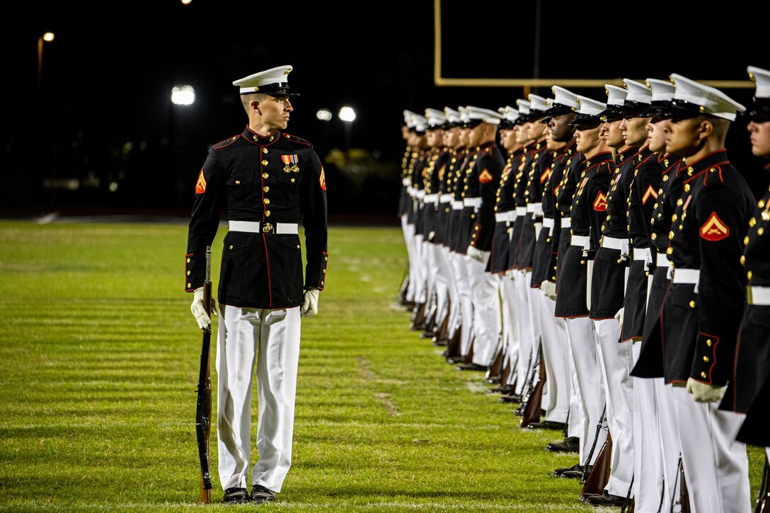 Corporal Blake A. Behrens, number two rifle inspector, Silent Drill Platoon, conducts a rifle inspection during a Battle Color Ceremony at Kofa High School, Yuma, Ariz., March 3, 2022.