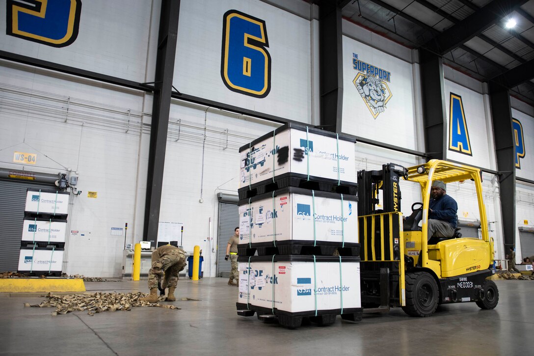 A man uses a forklift to move packages of body armor and helmets bound for Ukraine.