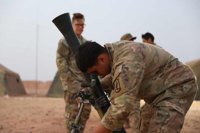 A soldier looks into the eyepiece of a weapon.