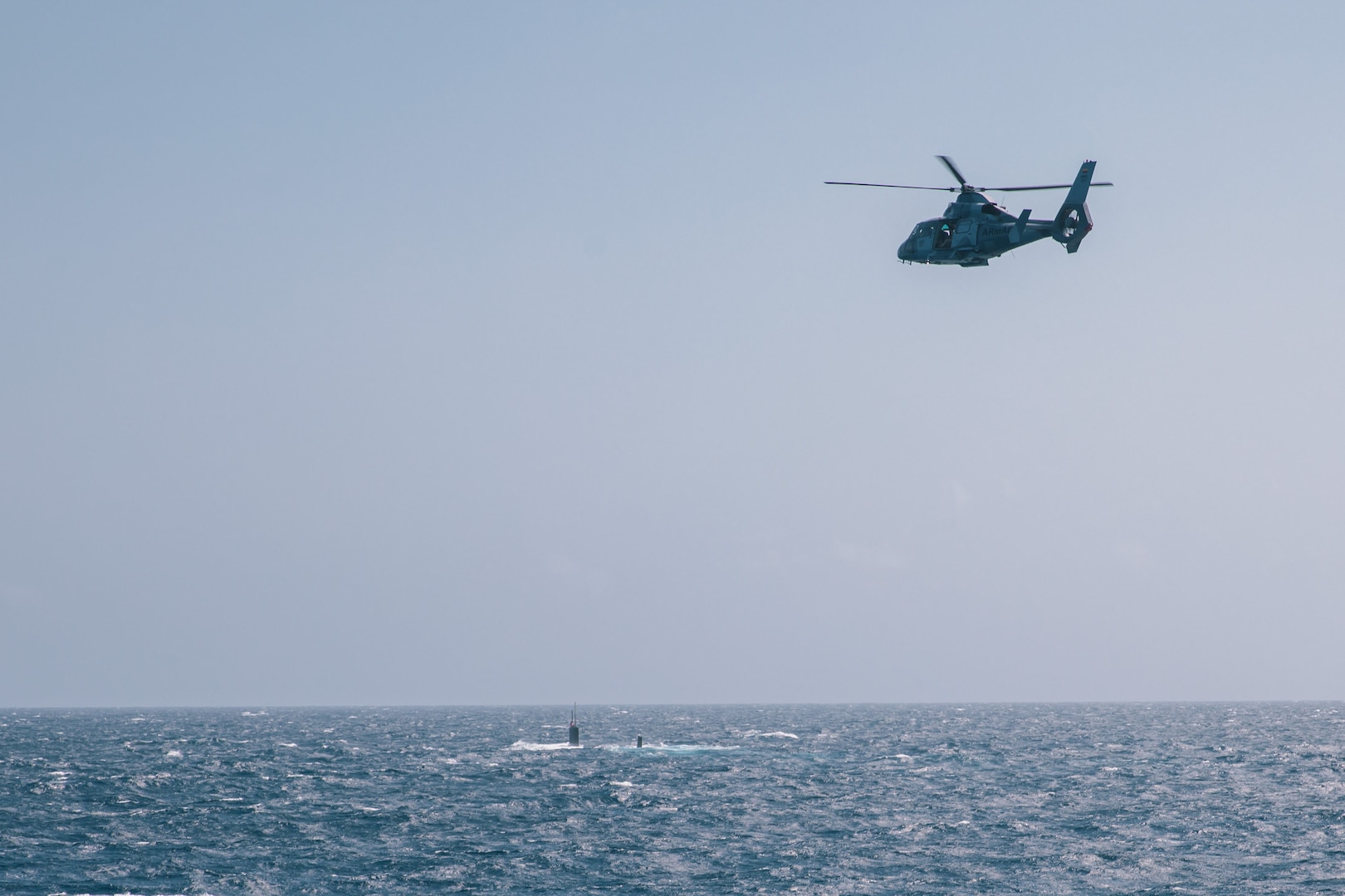 A military helicopter flies over the Virginia-class fast attack submarine USS Minnesota (SSN 783) during a bilateral anti-submarine warfare exercise with the Colombian navy, Feb. 27, 2022.