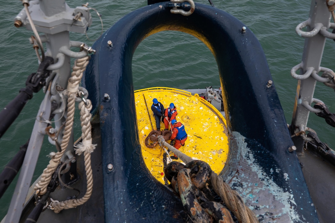 Sailors secure a ship to a buoy.