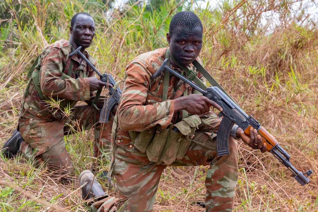 Soldiers kneel with weapons.