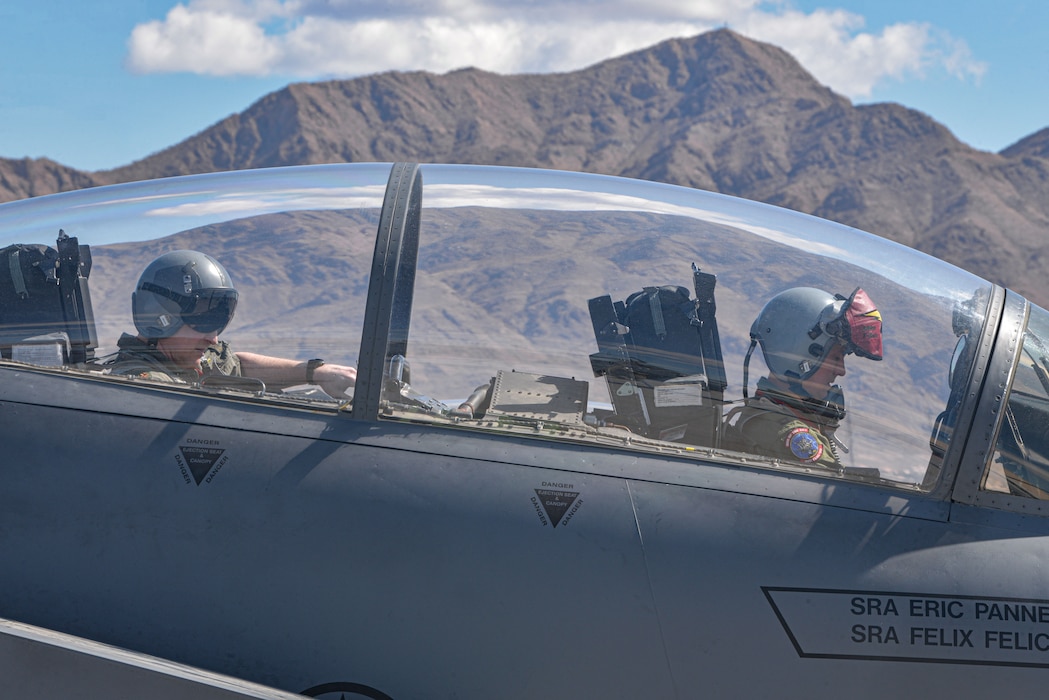A U.S. Air Force pilot and a U.S. Air Force Weapons Systems officer complete pre-flight checks by flying an F-15E Strike Eagle jet.