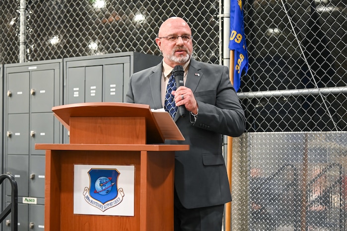 Harry Briesmaster speaks into a handheld microphone from behind a podium.