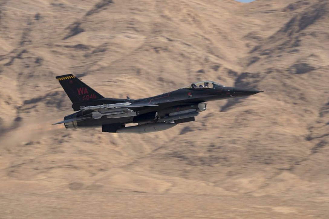 An aircraft flies near mountains.