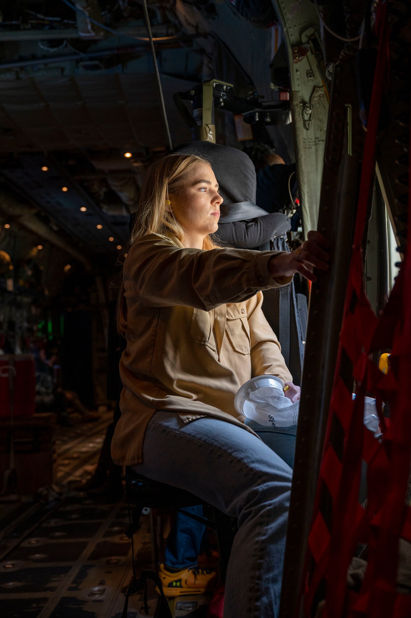 A service member’s family member looks out the window of a C-130J Super Hercules